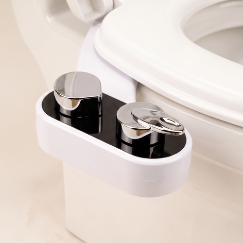 Bidetly Warm bidet attachment mounted under a toilet seat, showing the black control panel and two chrome dials